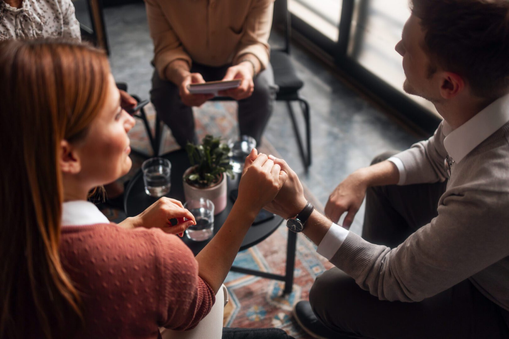 People holding hands in a supportive meeting.