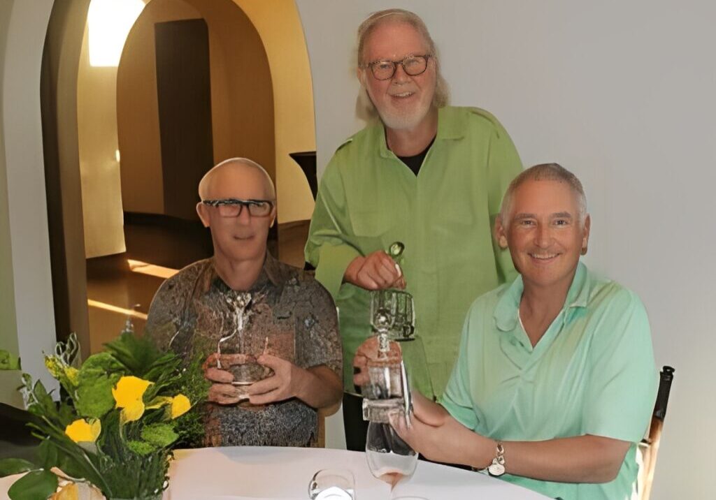 Three men posing with glass awards.