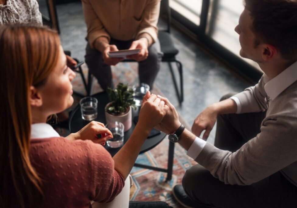 People holding hands in a supportive meeting.
