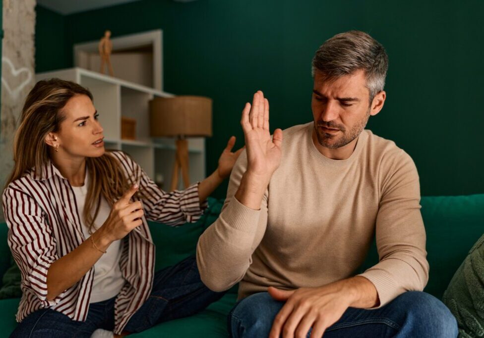 Couple arguing on a green sofa.